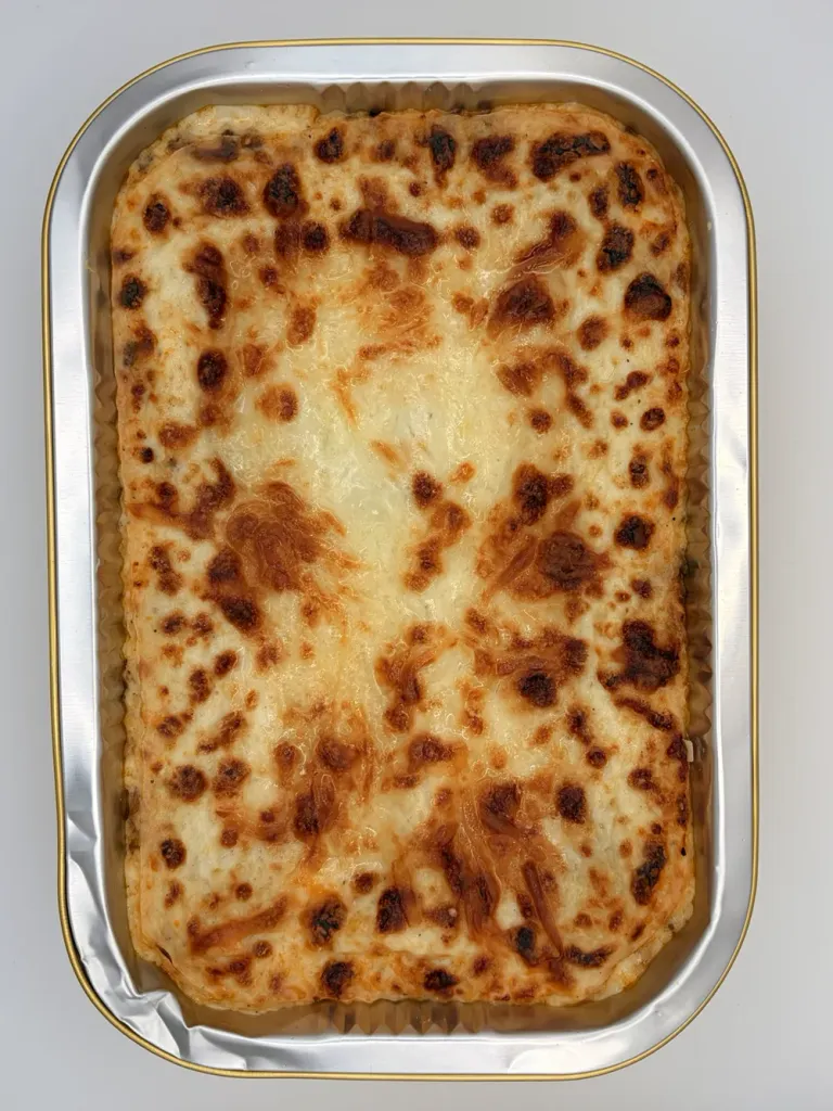 A baked Beebti beef béchamel lasagna in its foil tray, golden on top